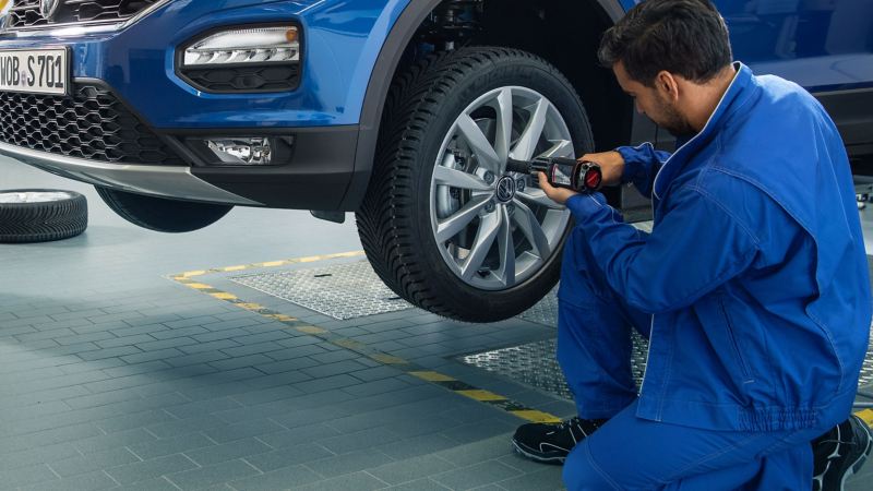 Un Réparateur Agréé  Volkswagen dans son atelier est en train d'intervenir sur un pneumatique