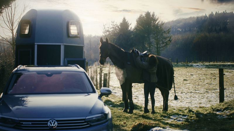 Janina Sandvoß saddles her horse and prepares it for the ride, next to her stands her VW Passat B6 with horse trailer