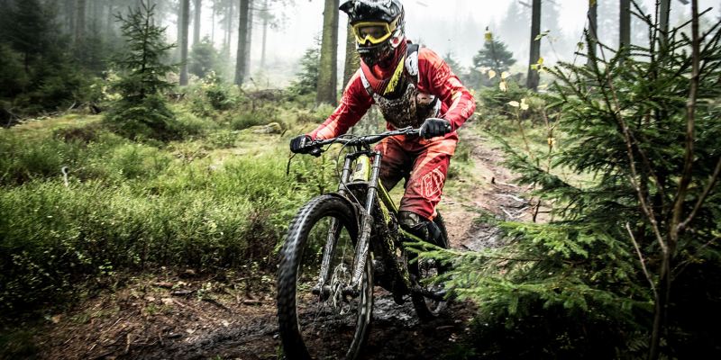 Christian Junker rides his mountain bike along a muddy track in a forest