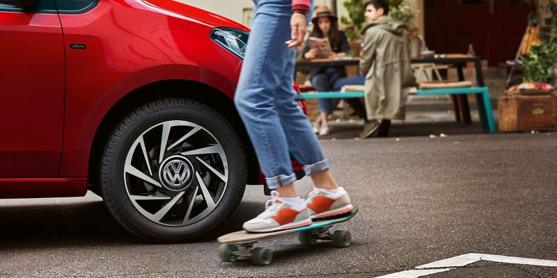 Une femme en skateboard passe devant une Volkswagen Up!