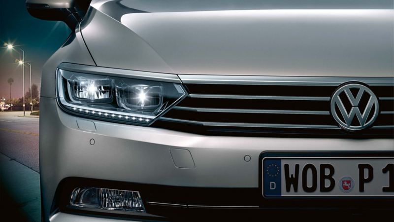 Dettaglio del faro anteriore destro di un'auto Volkswagen, di notte, con anabbaglianti permanenti accesi.
