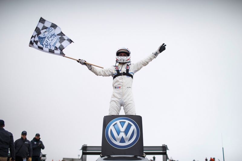 Romain Dumas schwenkt die Zielflagge auf dem Auto