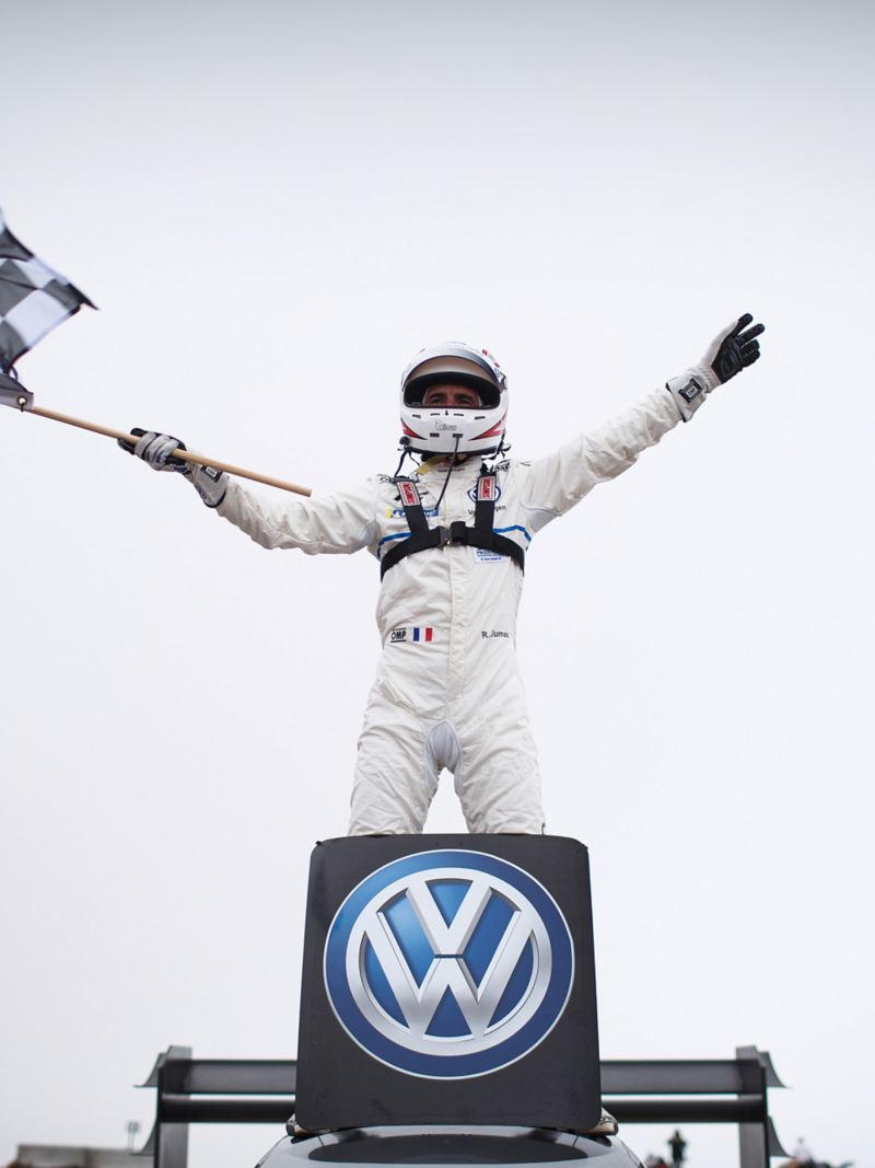 Romain Dumas schwenkt die Zielflagge auf dem Auto