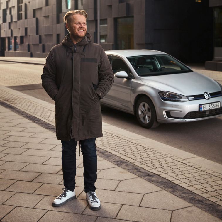 Ginge is standing on the side of the street next to his e-Golf.