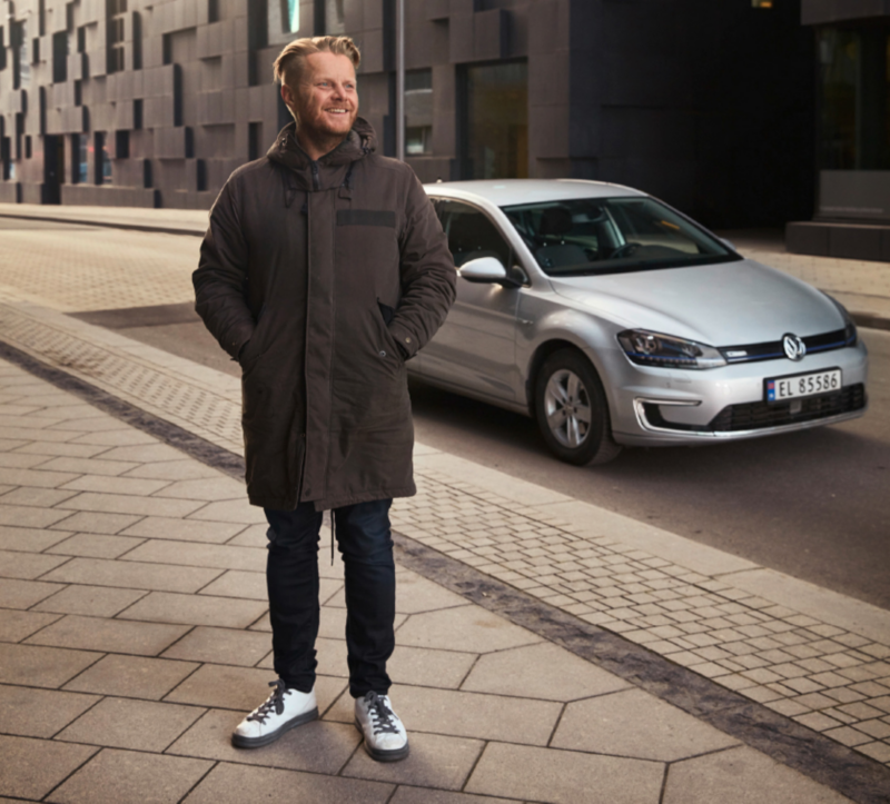 Ginge is standing on the side of the street next to his e-Golf.