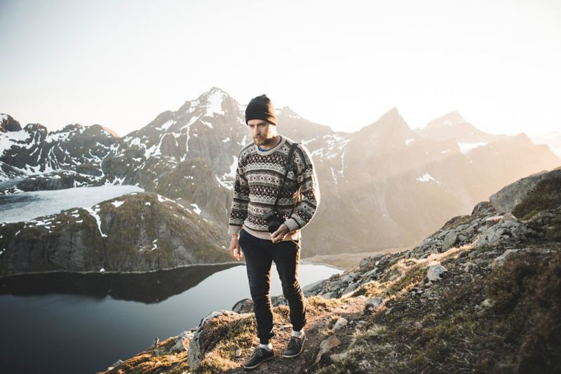 Uomo con maglione tipico norvegese e sullo sfondo una catena montuosa