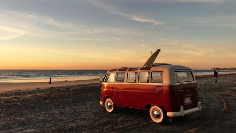The retro Bulli with an electric motor parked at the beach at sunset.