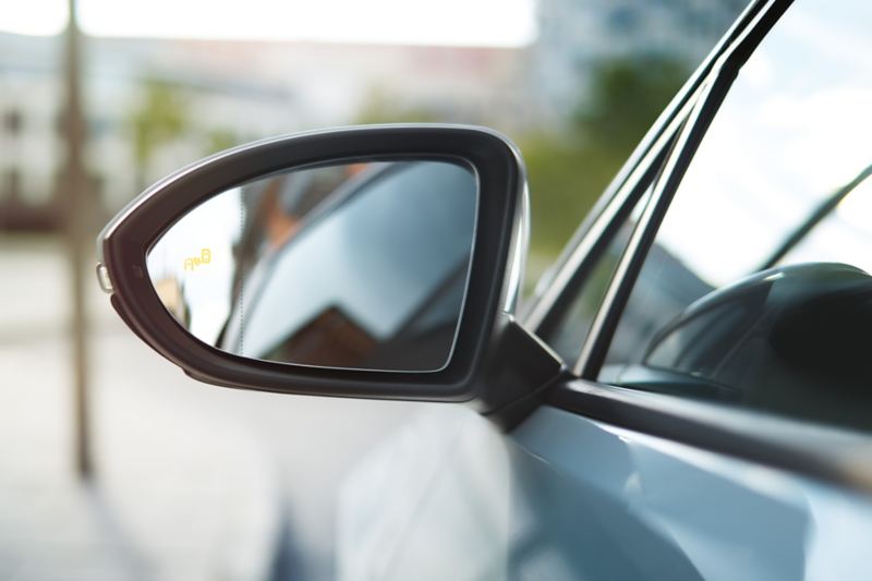 Dettaglio dello specchietto retrovisore esterno sinistro di un'auto Volkswagen.