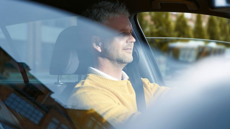 Uomo con pullover giallo alla guida di una Volkswagen