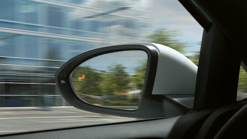 Linker Außenspiegel vom Fahrerplatz aus gesehen mit leuchtendem Symbol des "Blind Spot"-Sensors