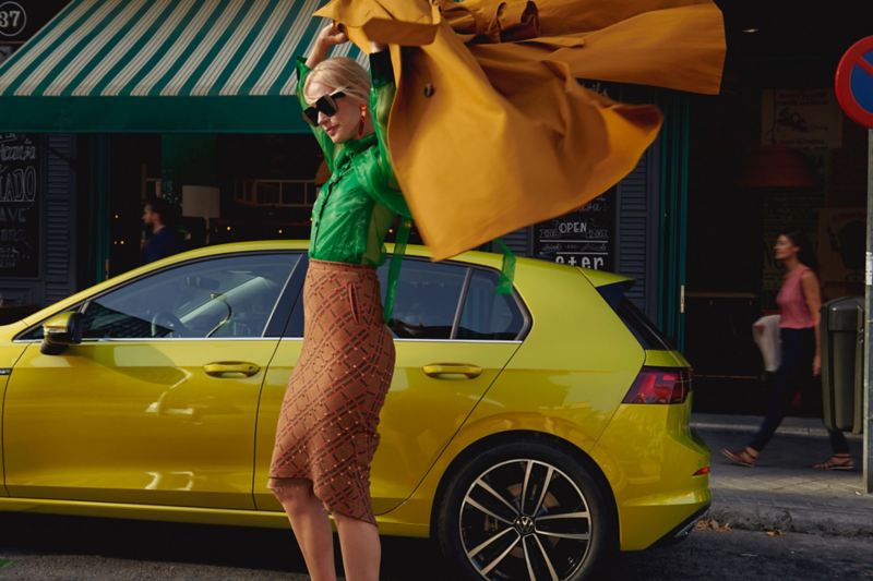 Vista lateral de VW Golf está en una calle, frente a una mujer