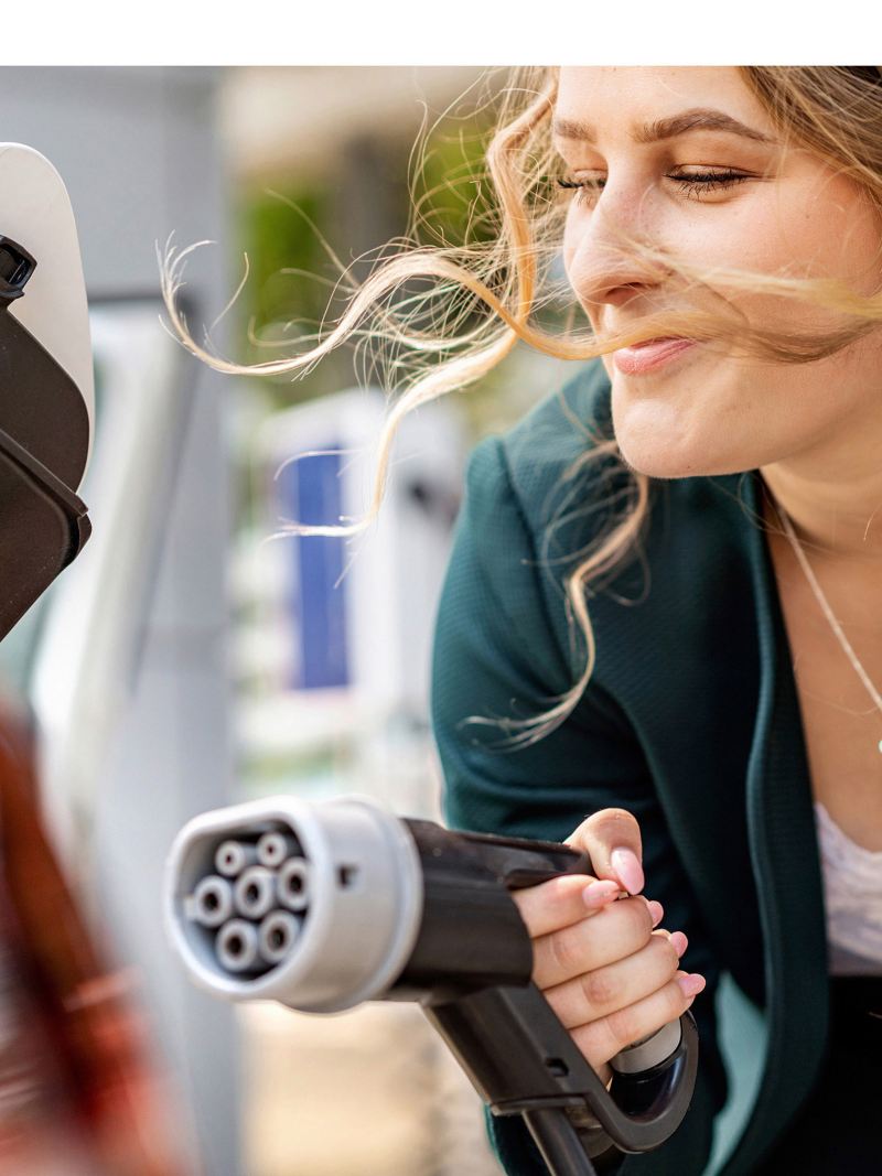 Woman with charging connector for an electric car in her hand