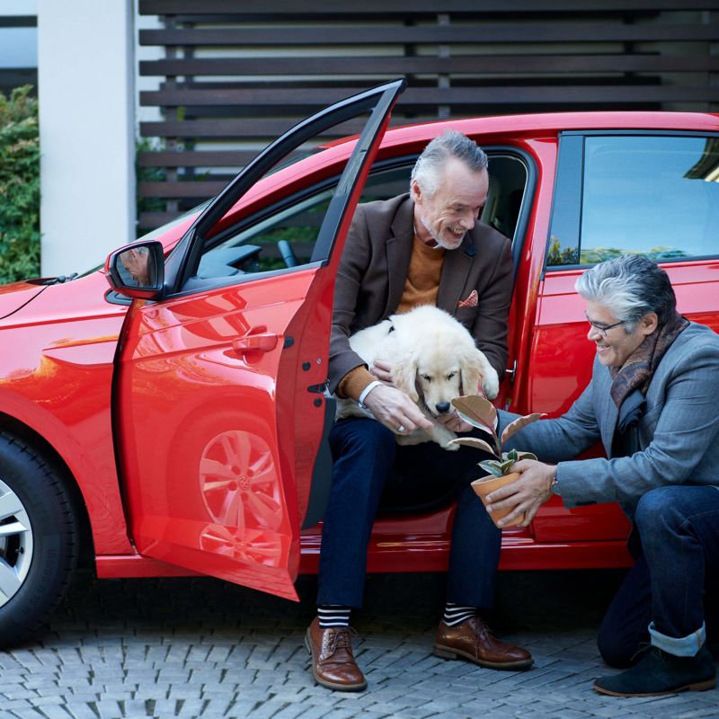 A man sat in a car and holding a dog