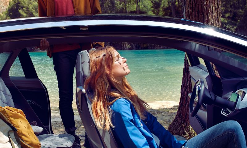 Mann und Frau entspannen mit ihrem Volkswagen am See