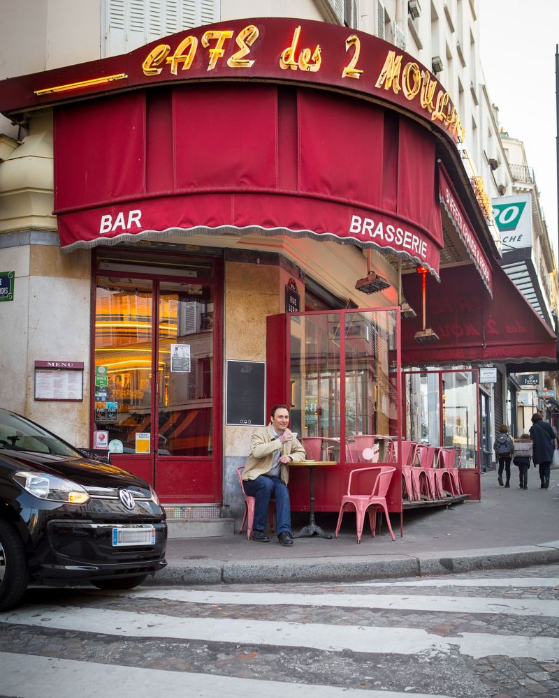 Alexandre Marie sidder foran en café, og hans e-up! holder parkeret ved siden af.