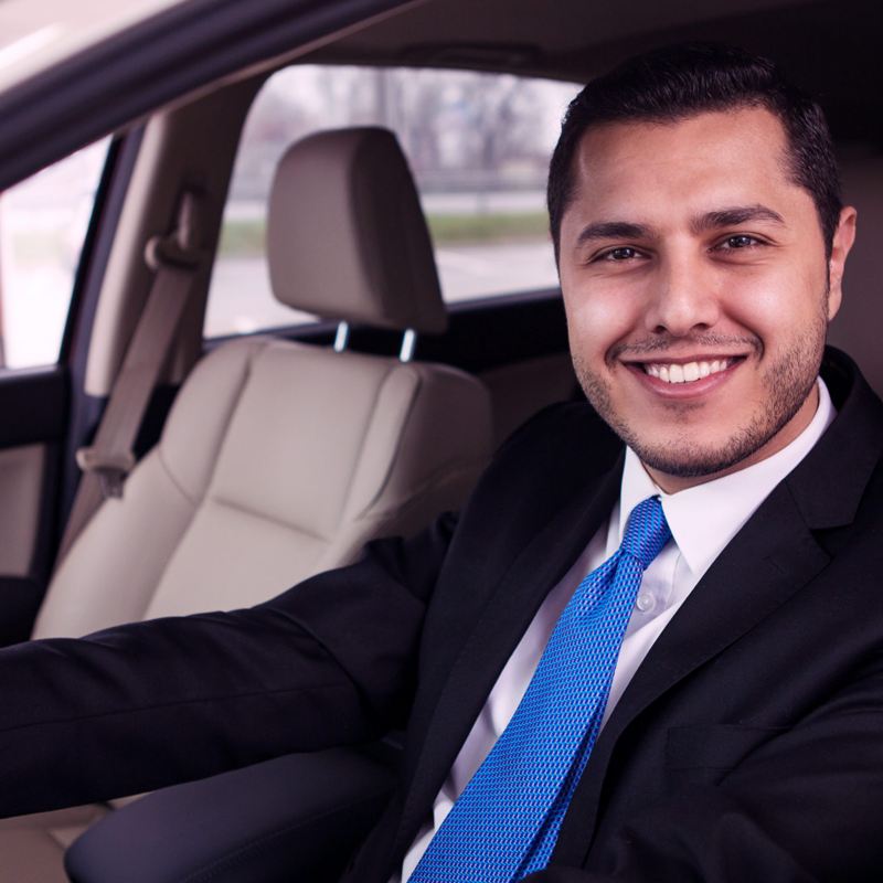Joven sonriente al volante de un auto nuevo adquirido con My Leasing de Servicios Financieros Volkswagen