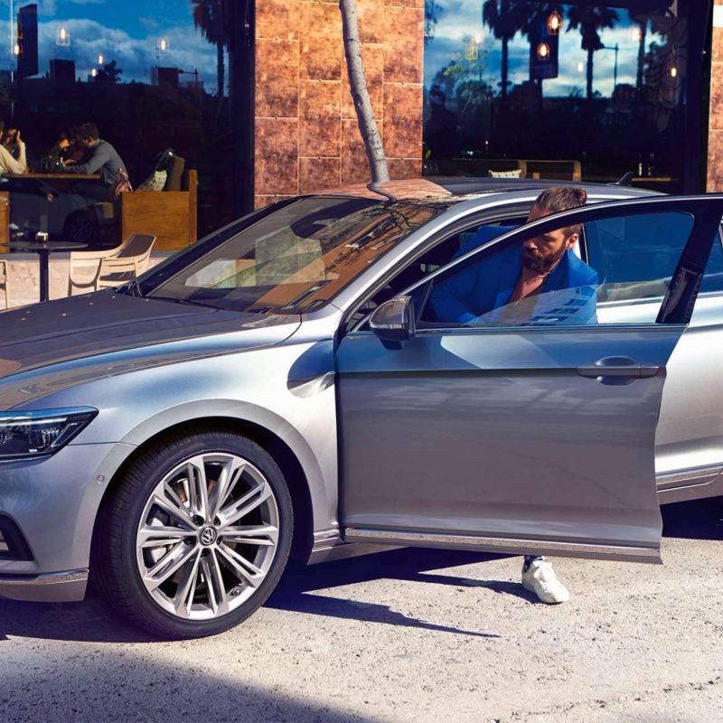 Un ragazzo entra nella sua auto Volkswagen Passat 
