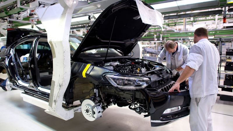 Two Volkswagen employees assembling the front section of a Passat