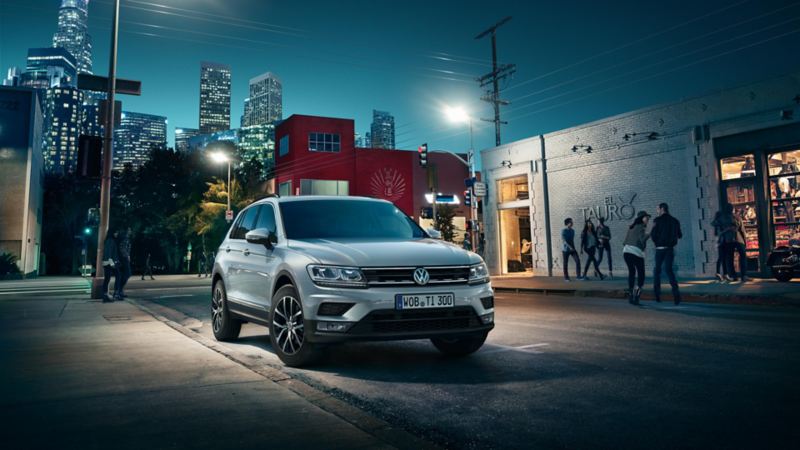 VW Tiguan parking on a road, people standing in front of a shop