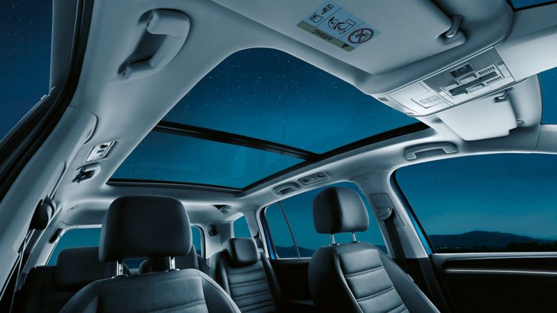 Kabinen i VW Touran med syv sæder, fokus på det åbne panoramatag (ekstraudstyr) og derigennem kig til stjernehimlen.