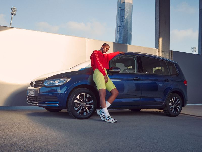 Mann lehnt an Kotflügel von VW Touran UNITED