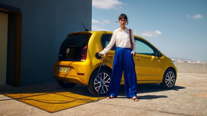 Une femme en train de charger la VW e-up! jaune