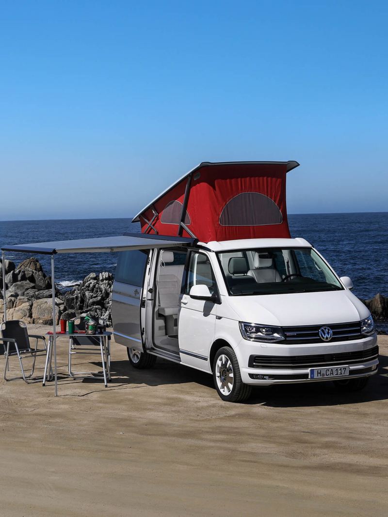 VW T3 and T6 California camper vans parked by ocean