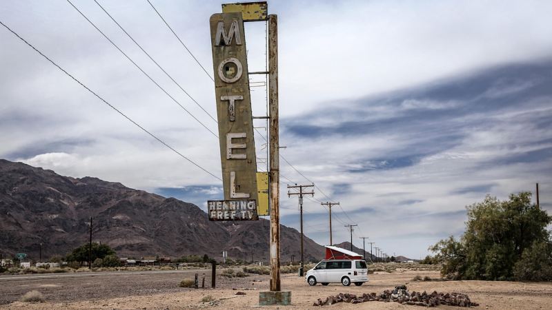 VW California parked by historic neon motel sign