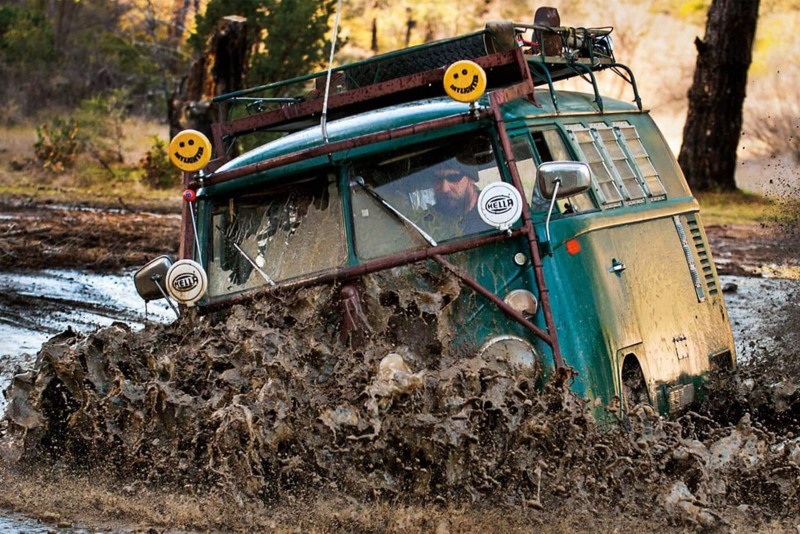 Green camper van driving through mud