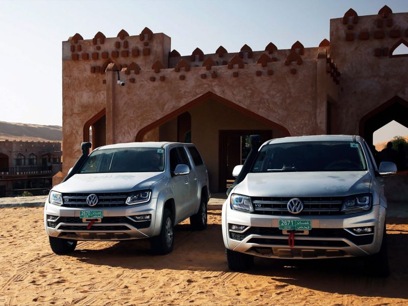 Two grey Amarok front view next to a middle-eastern style building