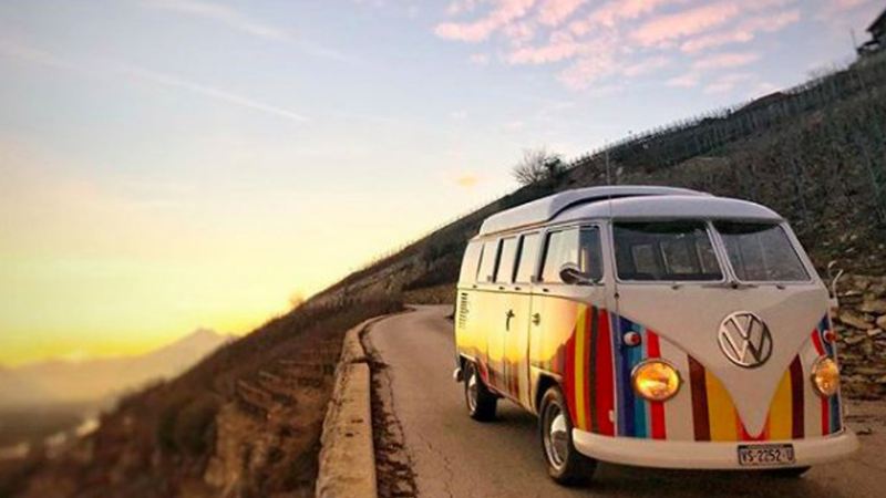 Stripey campervan driving on road with sunset background