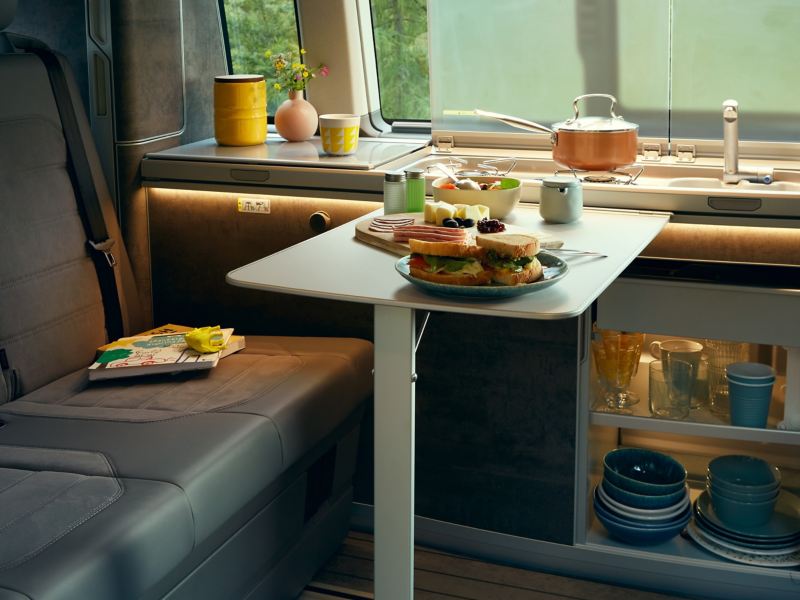 Köksdesignen i VW California campingbil visar det utdragbara bordet och förvaringsskåpen under