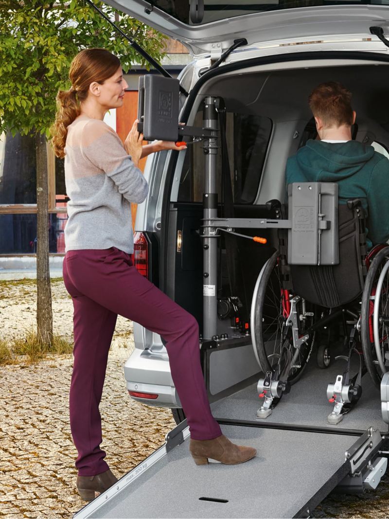 Rullstol kör uppför rullstolsrampen i en handikappanpassad VW Caddy