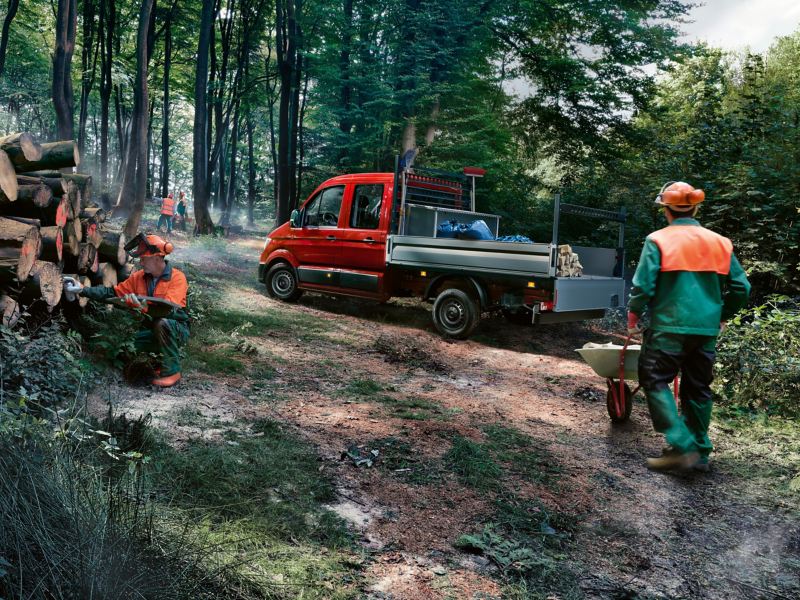 VW Crafter Flak i skogen omgiven av skogsarbetare