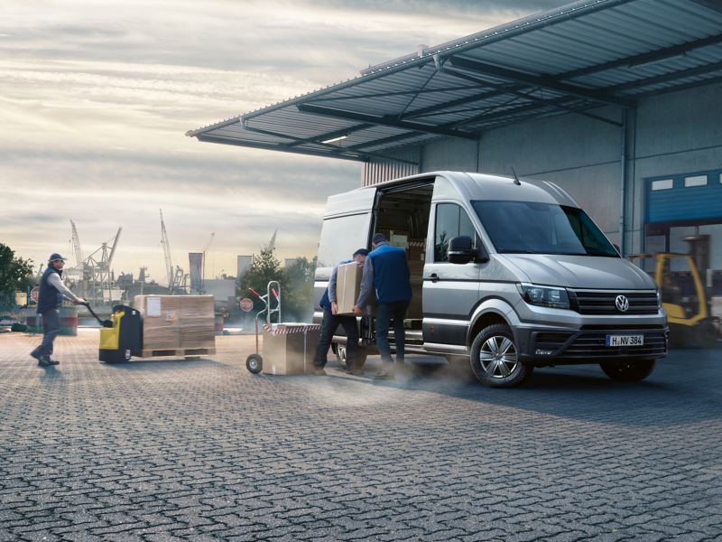 Le Crafter Van de Volkswagen Véhicules Utilitaires devant un hall. Des colis sont en train d'être chargés.