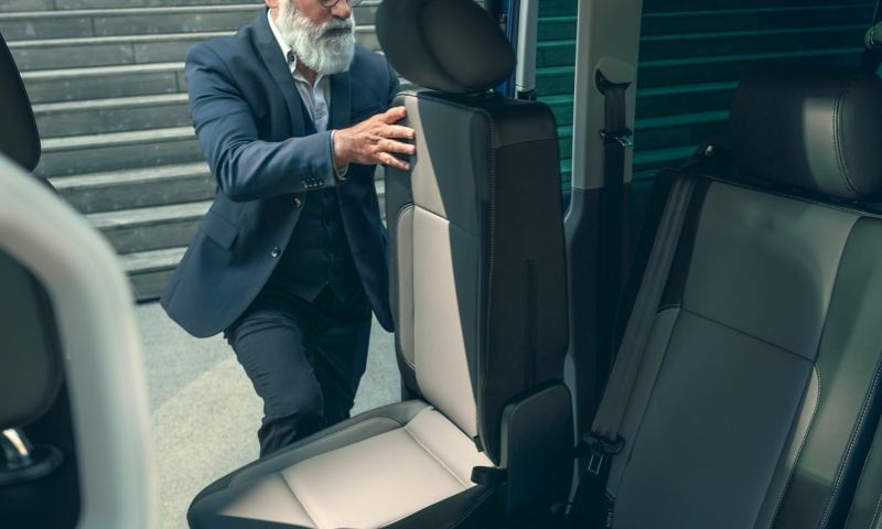 Ein Mann verstellt einen Sitz im Fahrgastraum eines Fahrzeugs.