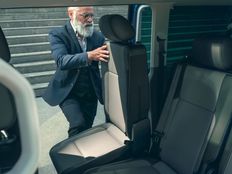 Ein Mann verstellt einen Sitz im Fahrgastraum eines Fahrzeugs.