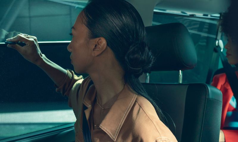 Eine Frau betätigt ein Rollo im Inneren eines Fahrzeugs.