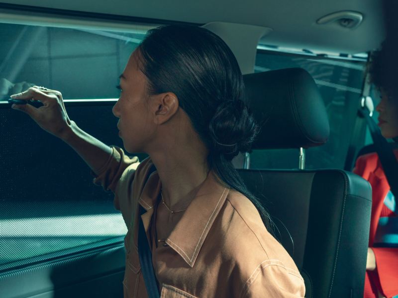 Eine Frau betätigt ein Rollo im Inneren eines Fahrzeugs.