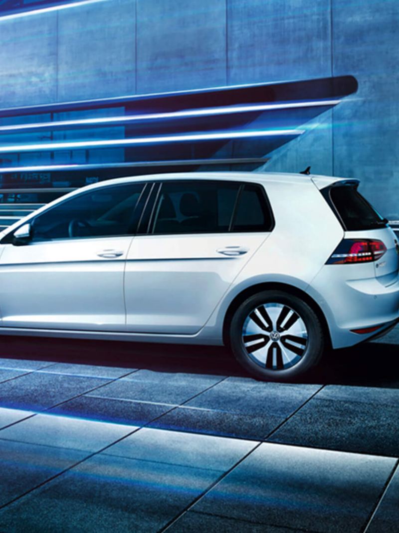Profile shot of a white Volkswagen e-Golf, in an industrial setting..