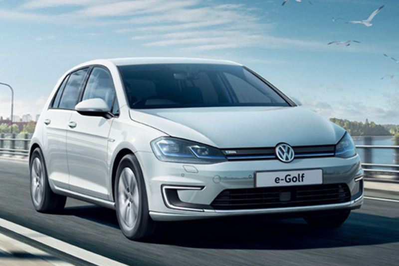 Front shot of a white Volkswagen e-Golf driving across a bridge.