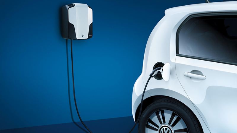 A white Volkswagen e-up! charging, using a wall mounted charge point.