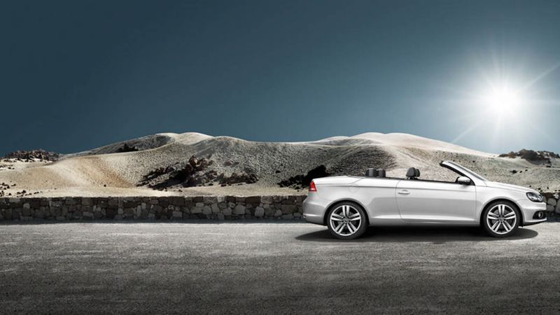 A silver Volkswagen Eos, parked in the desert, the roof down.