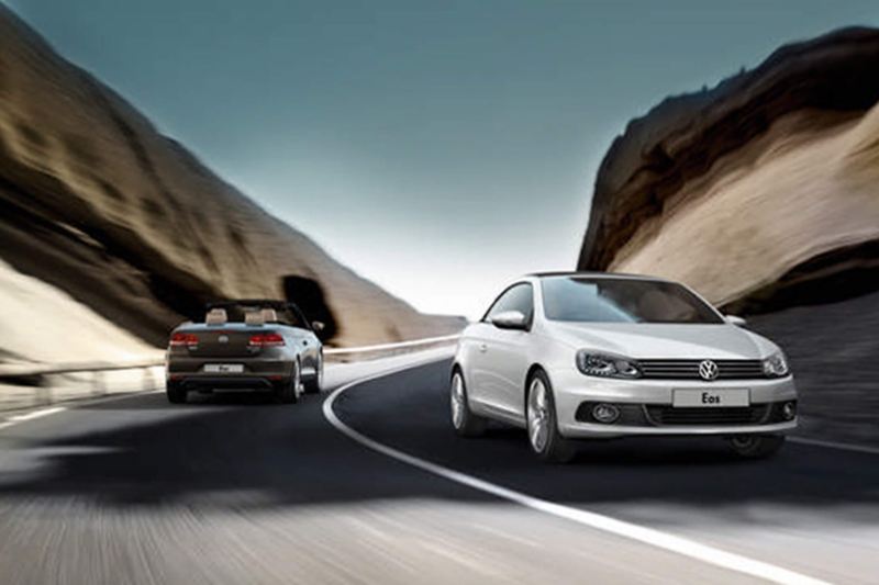Two Volkswagen Eos' driving in opposite directions, through the mountains.
