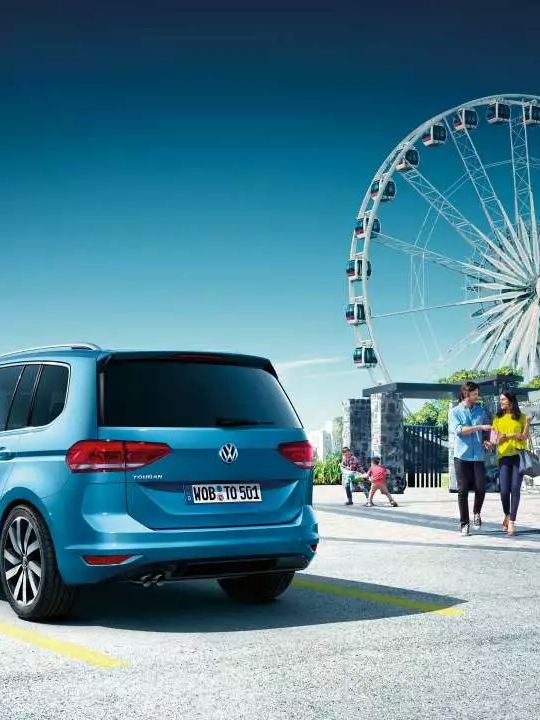 VW Touran bleu stationné devant une grande roue