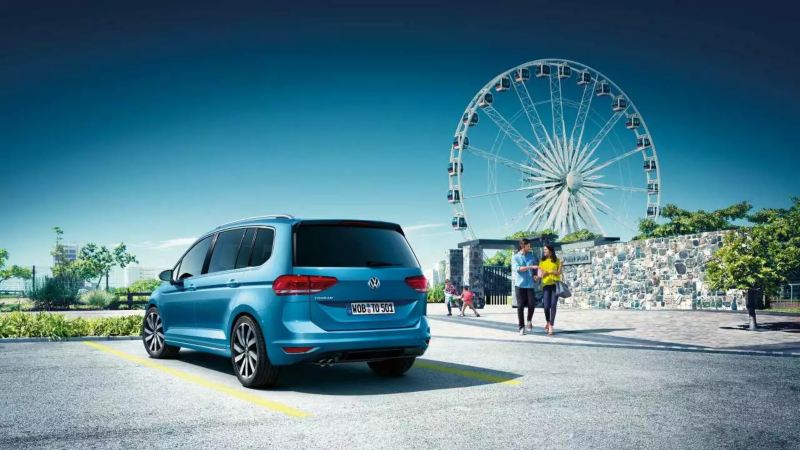 VW Touran bleu stationné devant une grande roue