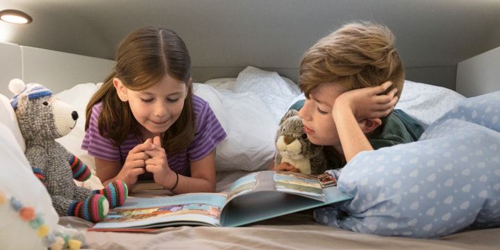 Ein kleiner Junge und seine Schwester liegen im Hochbett des Grand California und lesen gemeinsam ein Buch.