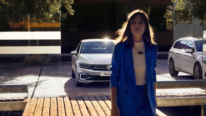 A lady in a suit walking away from a car park with the new Passat in the background