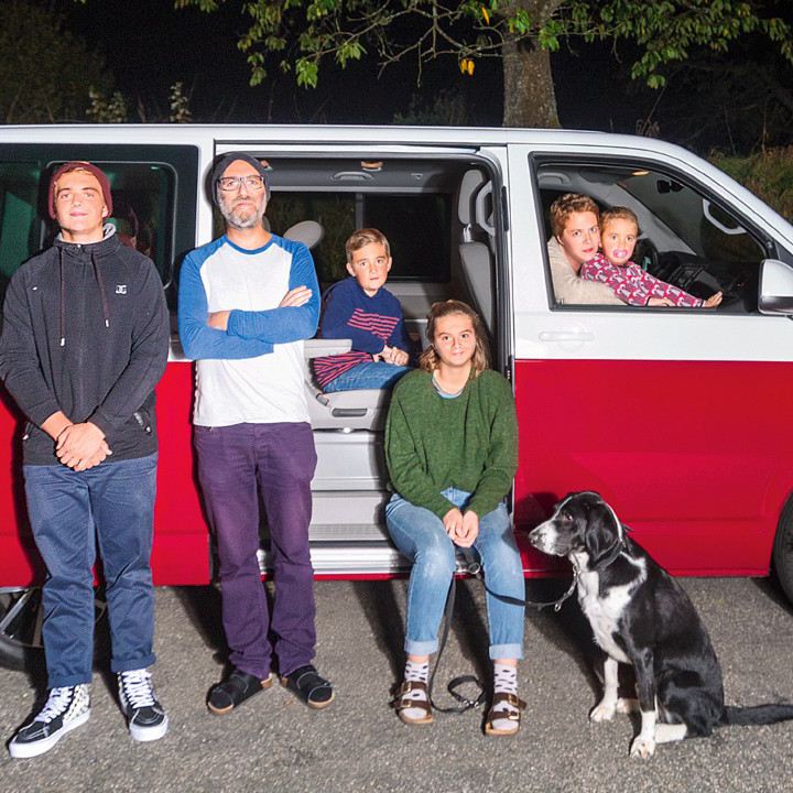 Eine Familie von sechs Personen steht vor einem parkierten Multivan