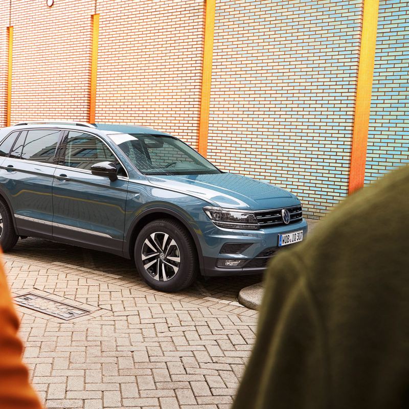 En Volkswagen Tiguan står parkerad på en gata. En kvinna och man syns i förgrunden.